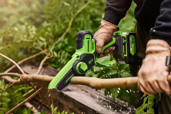 מסור שרשרת מיני 10 ס״מ 24 וולט נטען, Greenworks G24MCS10: חיתוך ענף על הקרקע בחורשה, המסור מוחזק ביד אחת עם כפפות עבודה