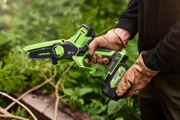 מסור שרשרת מיני 10 ס״מ 24 וולט נטען, Greenworks G24MCS10: חיתוך ענף דק שמוחזק ביד עם כפפת עבודה, הסוללה מחוברת למסור